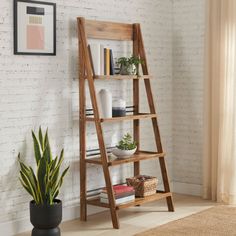 a wooden ladder shelf next to a potted plant in a room with white brick walls