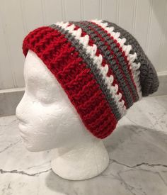 a white mannequin head wearing a red and gray crocheted beanie