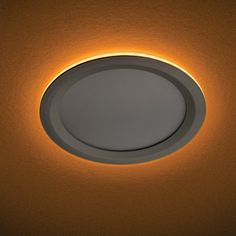 a round light fixture in the ceiling with dim lighting on it's side and an orange background