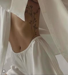 the back of a woman's white shirt with flowers on her chest and bottom