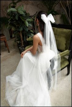 a woman in a wedding dress sitting on a couch with her back to the camera