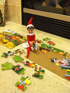 an elf is sitting on the floor next to some puzzles that are laid out