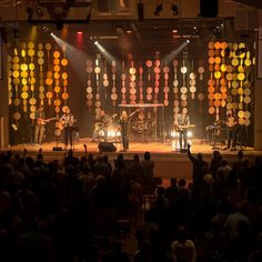 a group of people that are standing on a stage in front of a crowd and some lights