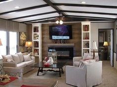 a living room filled with furniture and a flat screen tv mounted to the wall over a fireplace