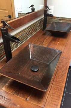 two bathroom sinks sitting on top of a wooden counter next to a mirror and faucet