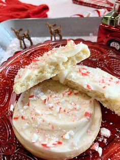 two cookies with white frosting and sprinkles sit on a red plate