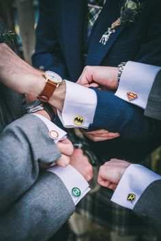 three men in suits are holding hands with badges on their sleeves and wristbands