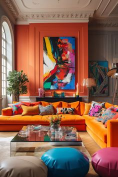 a living room with orange couches and colorful paintings on the wall behind them,