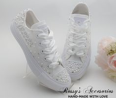 a pair of white tennis shoes with bows and pearls on the side, next to a bouquet of flowers