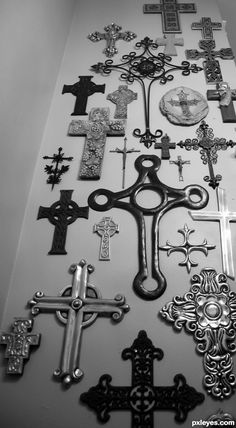 many crosses are arranged on the wall in this black and white photo, including one with an ornate cross