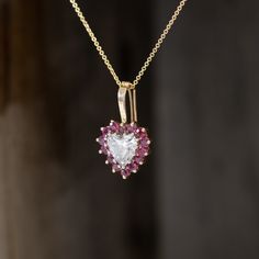 We can’t seem to get enough of the heart motif in jewelry - we’re big fans and think you should be too.This icy heart cut diamond with a juicy ruby surround suspended off a rich yellow gold bale is absolutely adorable. The prong-set rubies give the pendant an almost floral look, while the diamond center sparkles playfully in the light. We heart this heart! 14kt two-tone gold .9" in height 1.28ct Heart is estimated to be H color, I1 clarity, GIA standards. *Chain not included*Please see qualitati Heart Cut Ruby Jewelry, Heart-shaped Ruby Jewelry With Prong Setting, Heart Shaped Ruby Jewelry With Prong Setting, Heart-shaped Ruby Jewelry With Center Stone, Heart Cut Ruby Jewelry With Prong Setting, Ruby Heart Pendant, Modern Mens Rings, Art Jewelry Earrings, Ruby Heart