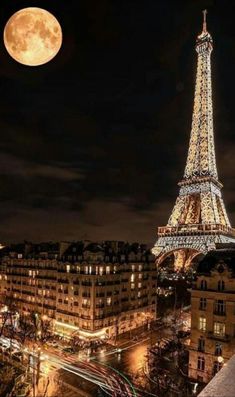 the eiffel tower lit up at night in paris, france with traffic passing by