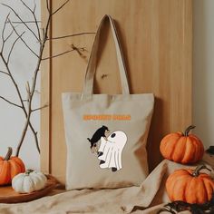 Meet your new favorite accessory! Our "Spooky Pals" tote bag features an adorable illustration of a cute ghost holding a dog, making it perfect for Halloween lovers and pet enthusiasts alike. Crafted from durable, high-quality materials, this tote is both practical and stylish. Carry your essentials with a touch of spooky charm and show off your love for your spooky pals! This 100% cotton bag comes in one size - 15" x 16" - perfect for everyday wear. While the canvas material will show off your designs in great colors, it's durable and will last for years. The bag features 20" handles (made from the same canvas), making it easy to carry even with a week's worth of shopping. .: 100% cotton canvas .: Heavy fabric (12 oz/yd² (406.9 g/m .: Sewn-in label .: Available in natural .: Spot clean on Halloween School Tote Bags, Trendy Halloween Tote Bag, Halloween Tote Bag For Daily Use, Halloween Tote Gift Bag, Halloween Gift Bag Tote, Cute Bags For Everyday Use And Halloween, Trendy Halloween Shoulder Bag For Daily Use, Trendy Rectangular Halloween Bag, Aesthetic Bag