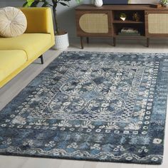 a living room with a yellow couch and blue rug