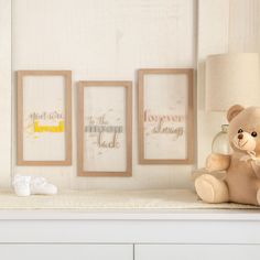 a teddy bear sitting on top of a shelf next to two framed pictures and a lamp