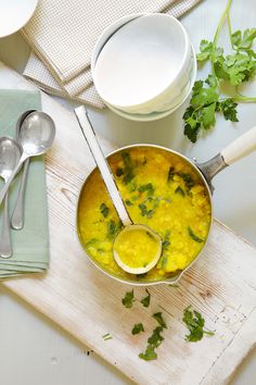 a pot filled with yellow food next to spoons