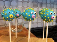 three cake pops with blue frosting and yellow sprinkles decorated as pigs