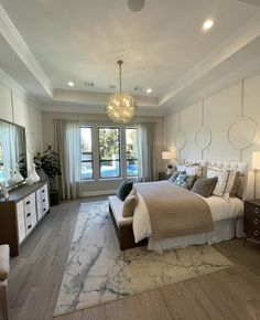 a bedroom with a large bed, dressers and a chandelier hanging from the ceiling