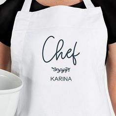 a woman wearing an apron holding a white bowl with the word chef written on it