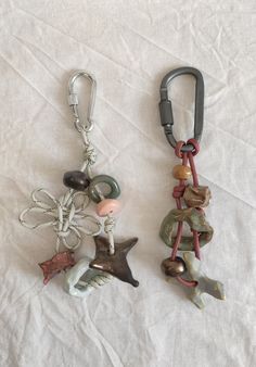 two key chains with charms attached to them sitting on a bed next to each other