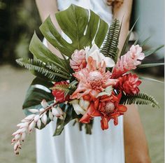 a bride holding a bouquet of flowers and greenery