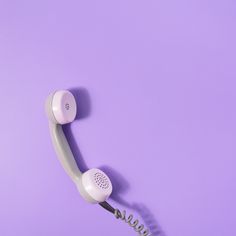 an old style telephone on a purple background with the phone cord still attached to it