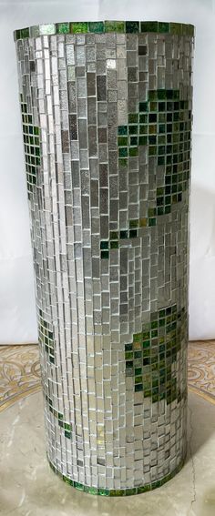 a glass vase sitting on top of a white table next to a tile wall and floor