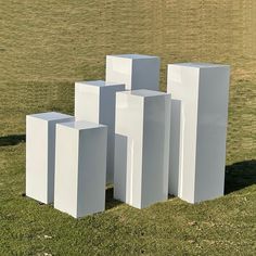 four white cubes are standing in the grass