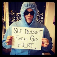 a man in a blue hoodie holding a sign that says she doesn't even go here