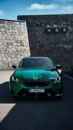 a green car parked in front of a stone wall