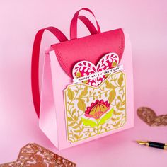 a pink and white bag sitting on top of a table next to some cards with hearts