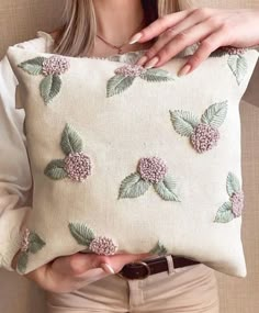 a woman holding a pillow with flowers on it