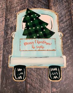 a merry christmas sign with a green tree on the front and blue back, hanging from a wooden wall