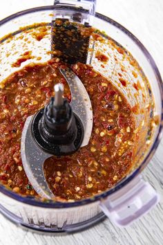 an overhead view of a food processor filled with red sauce and nuts, ready to be blended