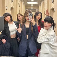 four women taking a selfie in a hallway with one woman holding up her phone