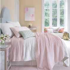 a bed with pink sheets and pillows in a bedroom