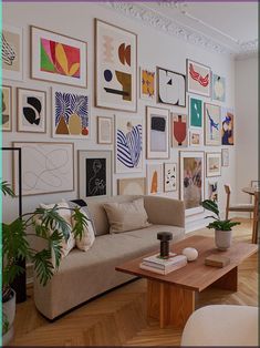 a living room filled with furniture and lots of pictures on the wall next to a coffee table