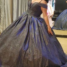 a woman in a blue ball gown looking at herself in the mirror