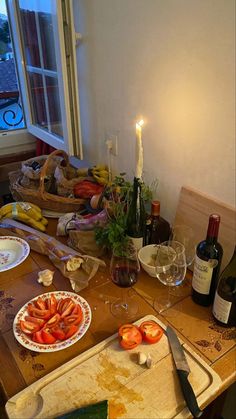 a table topped with plates and bottles of wine next to a window filled with food