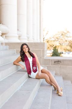 a woman is sitting on the steps in front of some columns and posing for a photo