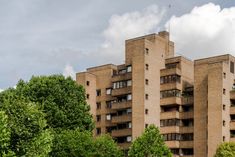 an apartment building with many windows and balconies on the top floor, surrounded by trees