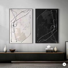 two black and white paintings hanging on the wall next to each other in a living room