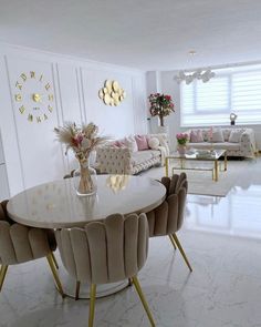 a living room filled with lots of furniture and flowers on top of a white table