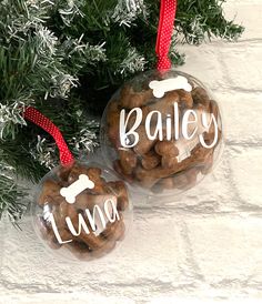 two personalized glass ornaments hanging from a christmas tree with dog bone and bones on them