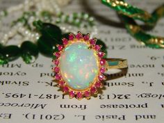 All Opals Are 100% Natural And Certified. Item details Sourced, Designed and Made BY Art Palace by MITIKA. Stone(s): Natural Fire Opal Total Weight : 4.49 Grams Material 925 Sterling Silver/14k Gold Silver/Gold Weight : 4.00Grams MAIN STONE INFORMATION Stone weight : 4.05 ct. Size : 10x12mm Shape : Oval Setting TypeProng Number Of Stones : 1 SIDE STONE INFORMATION Stone : Natural  Ruby Weight : 0.50 ct. Size : 1.50 mm Shape : Round Number Of Stones : 22 Custom Order-------    We can craft this r Oval Cluster Ring With 17 Jewels As Gift, Opal Ring With 17 Jewels For Wedding, Opal Wedding Ring With 17 Jewels, Hallmarked Opal Ring For Wedding, Hallmarked Opal Wedding Ring, Ruby Ring Engagement, Wedding Ring Opal, Opal Wedding Rings, Ring Opal