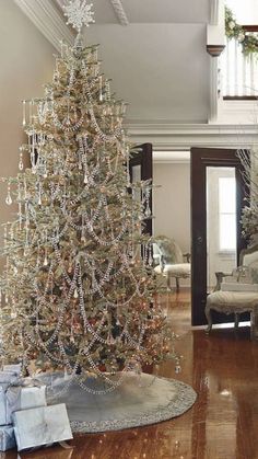 a white christmas tree in the middle of a living room with presents on the floor