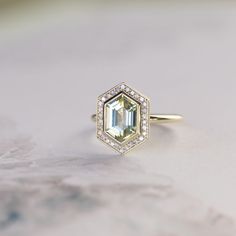 an emerald colored diamond sits on top of a gold ring with diamonds around the band