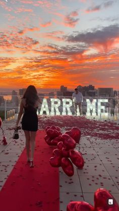 a woman walking down a red carpeted walkway with balloons in the shape of hearts