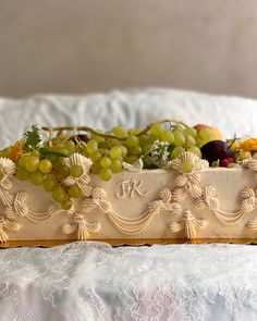 a tray with grapes and other fruit on it sitting on a white bed spreader