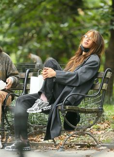 a man and woman sitting on a bench in the park with their heads covered by masks